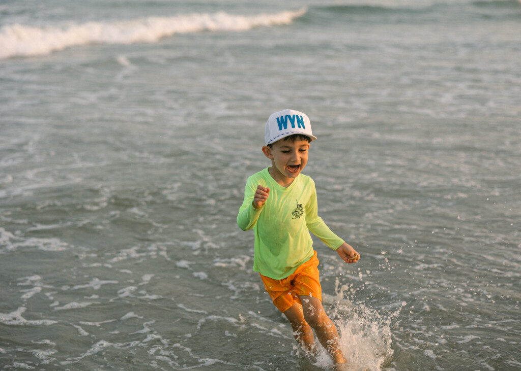 Candid moment of a child running through shallow waves at Sunset Beach, NC.