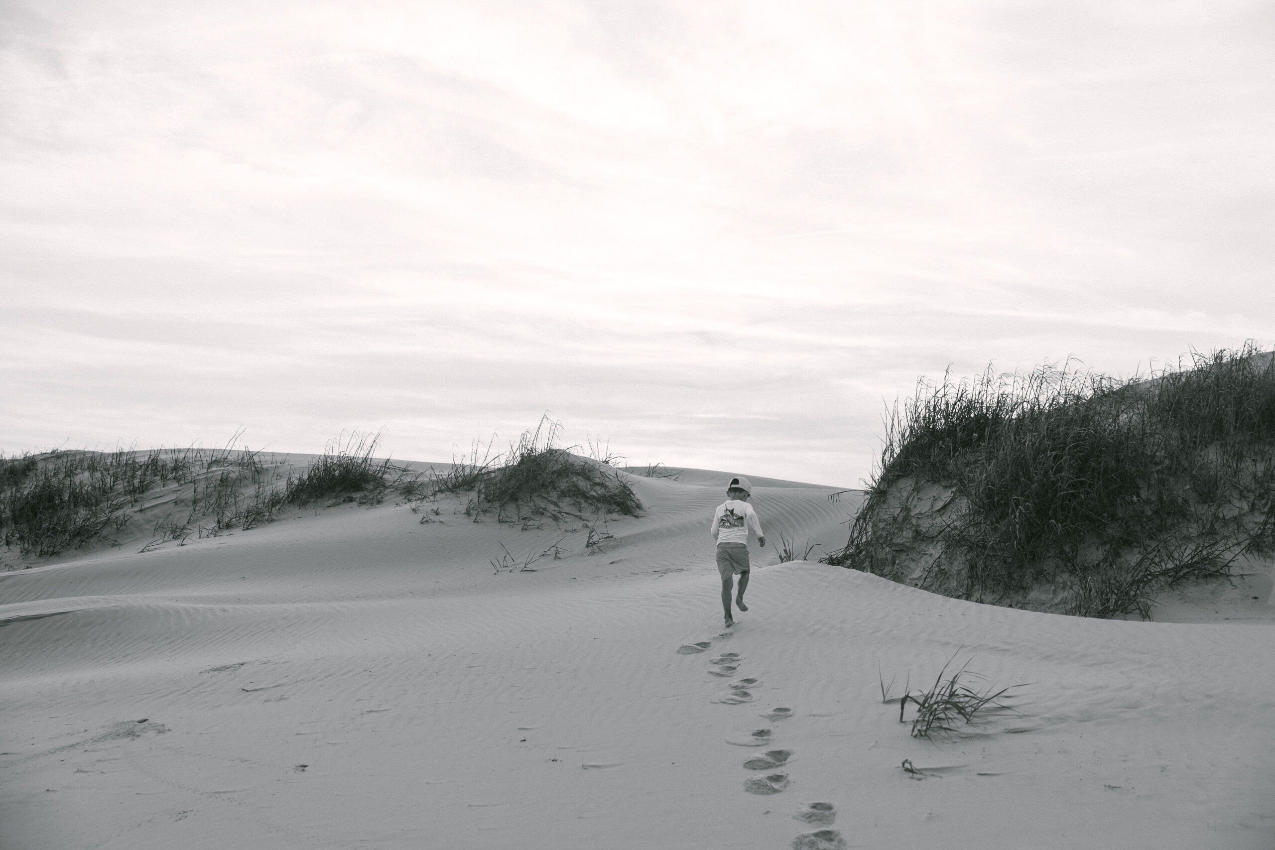 Child running on dunes Sunset Beach with soft pastel skies and wide open dunes in the background