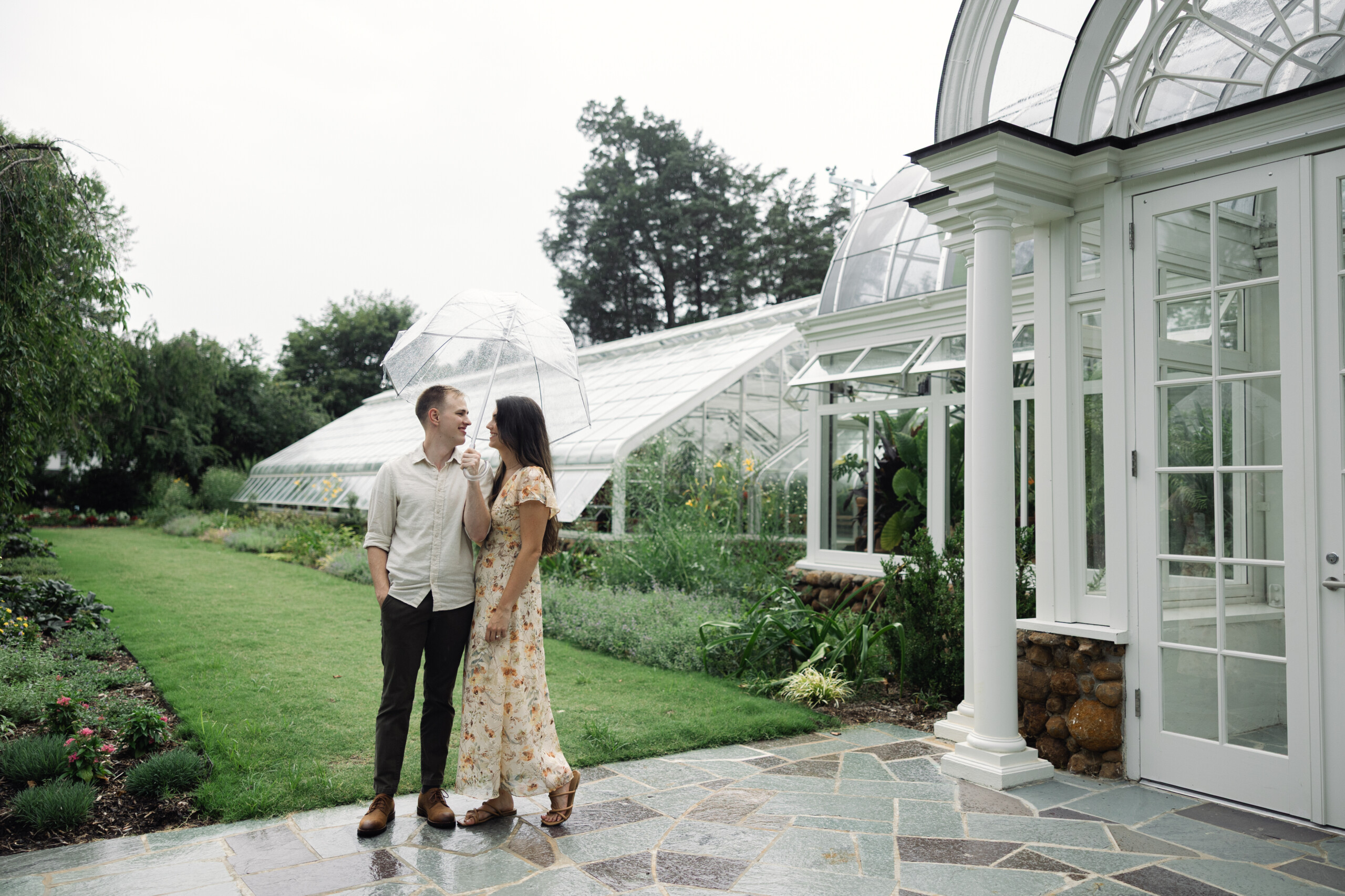 Couple embracing under a clear umbrella at Reynolda Gardens during a light rain