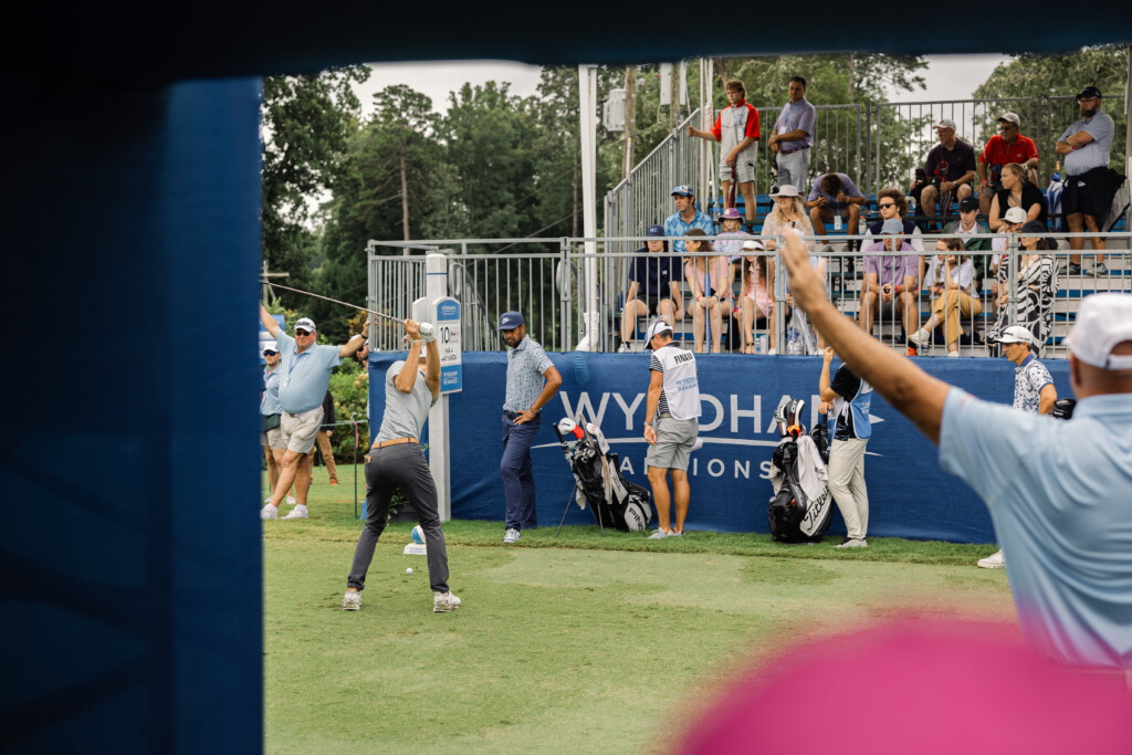 Vibrant crowd watching a golfer tee off at the Wyndham Championship