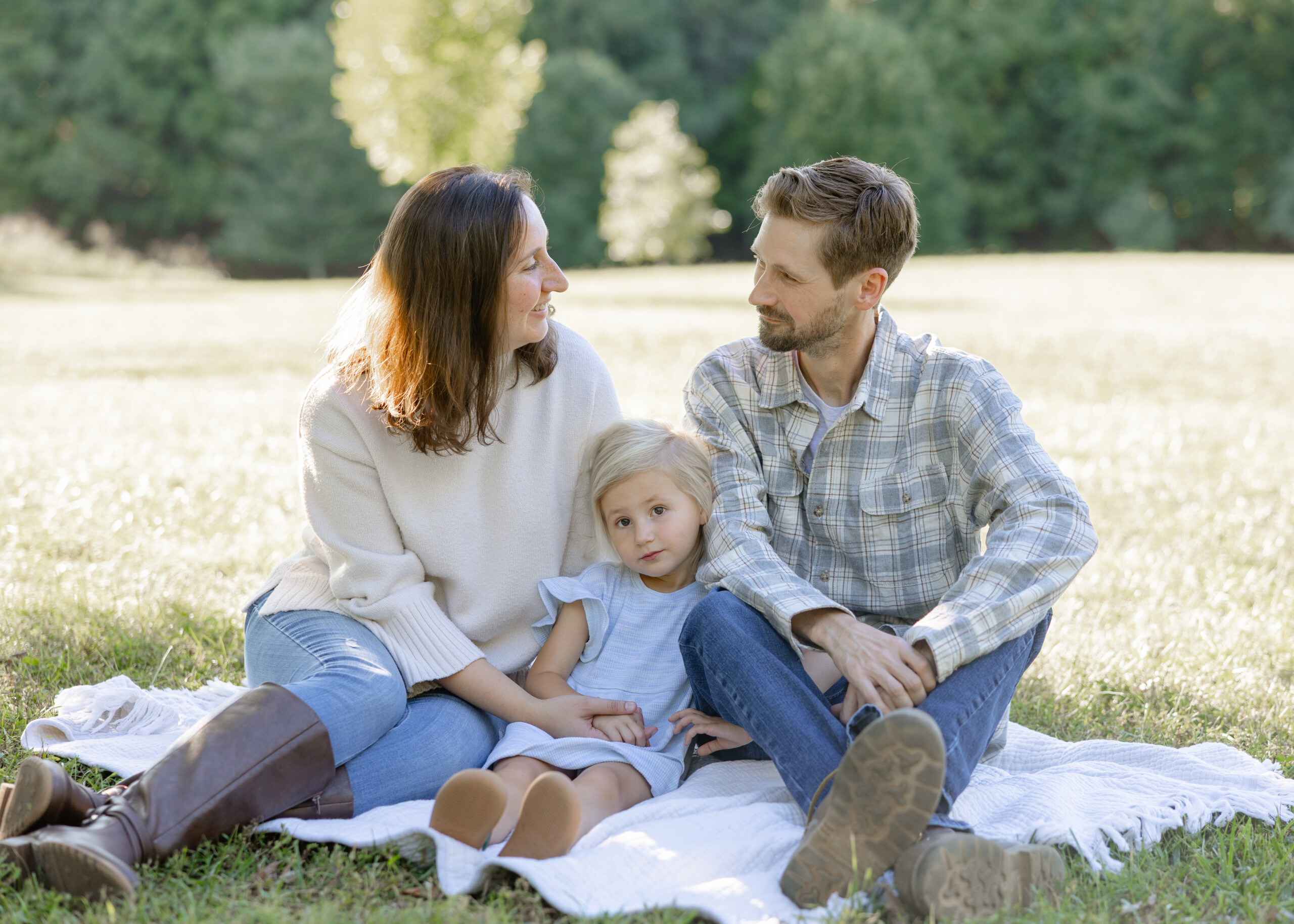 Family in coordinated neutral outfits walking through fall leaves in Greensboro